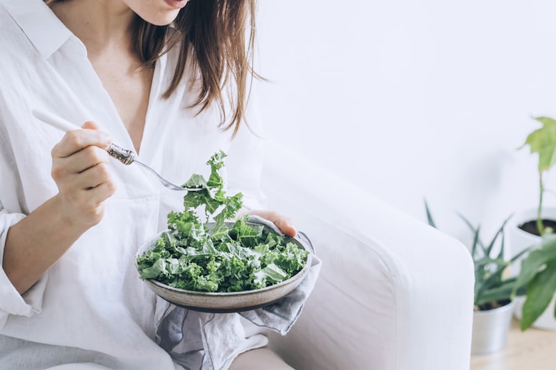 woman eating a bowl of fresh kale salad in white linen